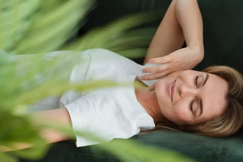 Femme allongée les yeux fermés profitant d’un moment de détente et de relaxation en sophrologie